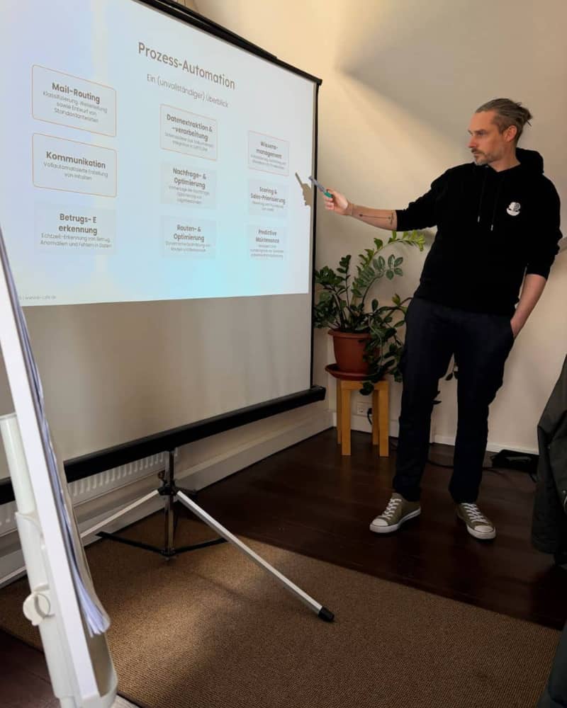 Christian Kleemann, Gründer und Geschäftsführer vom KI-Café bei einer Schulung vor einer Leinwand zeigt auf das Thema Prozess-Automation